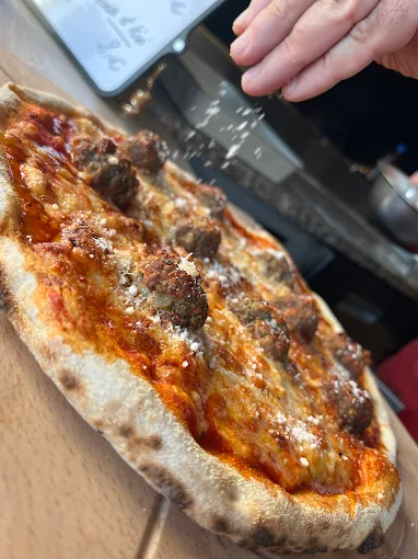 La Polpette, pizza signature, saupoudrée de parmesan à la sortie du four